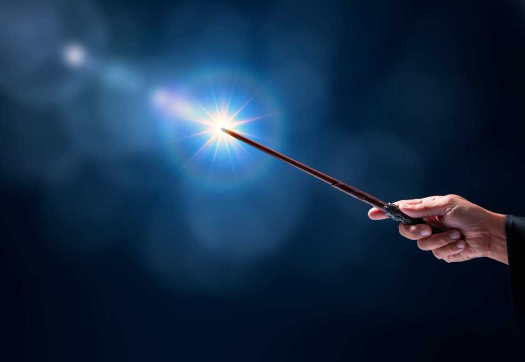 A hand hold a magic wand with sparklers on a dark blue background.