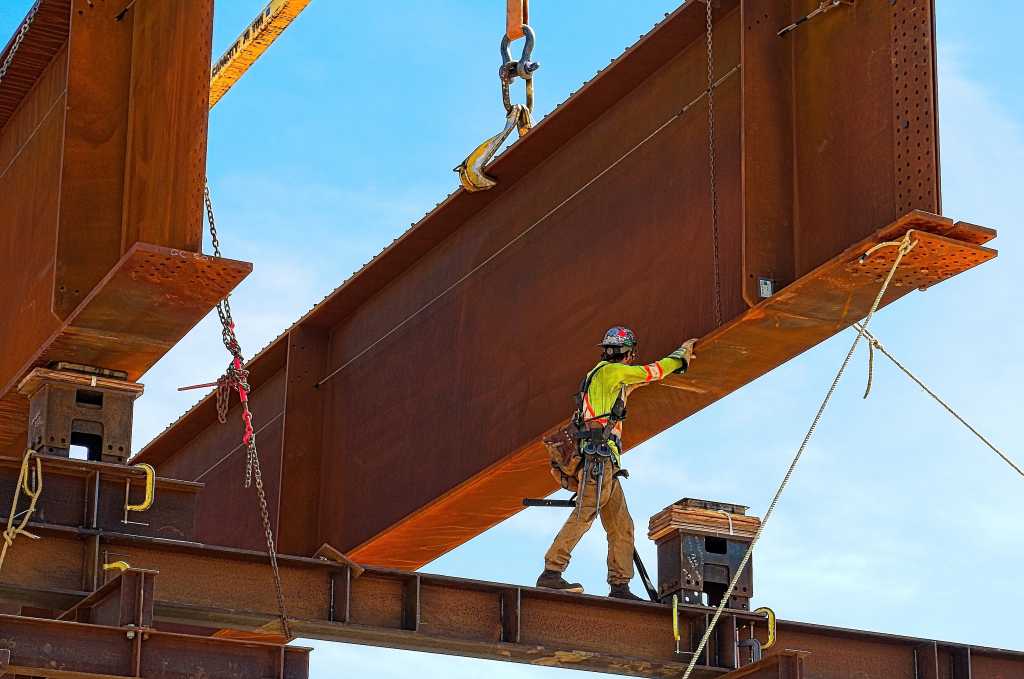 Rusty steel girder and two meter web installed on a bridge abutment and scaffolding as part of a new freeway interchange. Building construction infrastructure project.