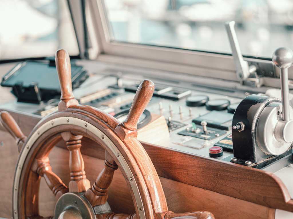 Close up of the interior of a large motor boat with wooden steering wheel.